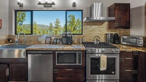 A modern kitchen with stainless steel appliances, a large window with a view, and wooden cabinetry. - New: Luxury Lakeview Cabin, Deck, Fireplace, View (Big Bear Lake)