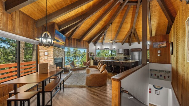 A spacious kitchen with modern appliances, a dining area with wooden tables and benches, and a cozy seating area with a fireplace. - New: Luxury Lakeview Cabin, Deck, Fireplace, View (Big Bear Lake)