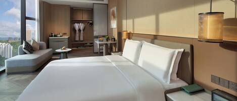 A modern hotel room with a large bed, a desk, a seating area, and a view of the cityscape.