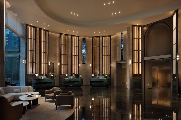 A spacious lobby with a reception desk, seating area, and a large window.
