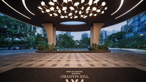 Entrada de hotel con piso a cuadros, un gran logotipo 'W' y un techo con una lámpara de diseño único.
