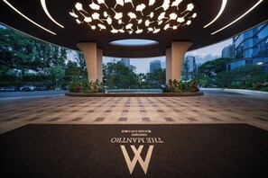 A hotel entrance with a checkered floor, a large illuminated ceiling, and a view of the cityscape.