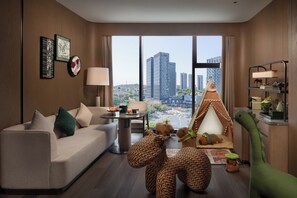 A modern hotel room with a sofa, a small table, a lamp, a tent, and a dinosaur toy.