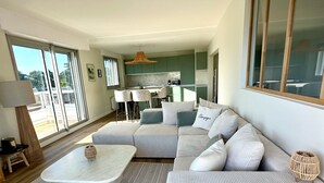 En moderne stue med en modulsofa, et sofabord og et spiseområde med et køkken i baggrunden.