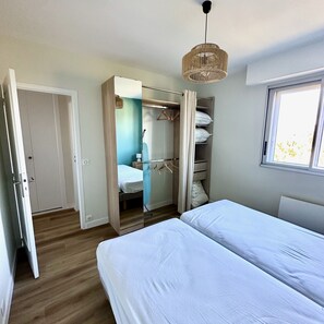A bedroom with a bed, a wardrobe, a hanging light fixture, and a window. - Le Pivoine : vue mer à La Baule (La Baule-Escoublac)