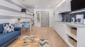 A modern kitchen with white cabinets, a grey backsplash, and a black TV mounted above the counter. - Comfortable Apartment | Pool | Close to the Beach (Pobierowo)
