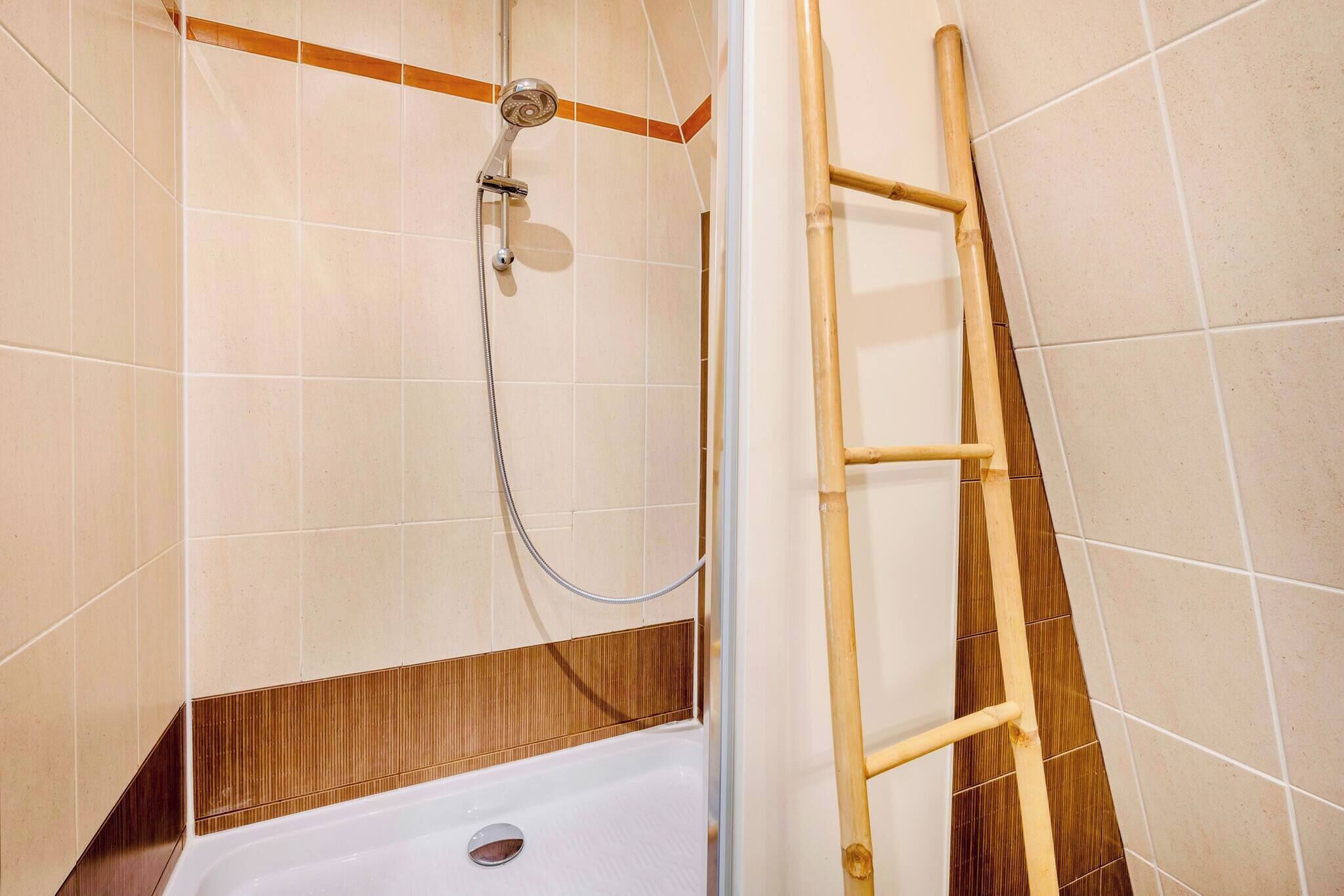 A shower with a wooden ladder, tiled walls, and a corner design.