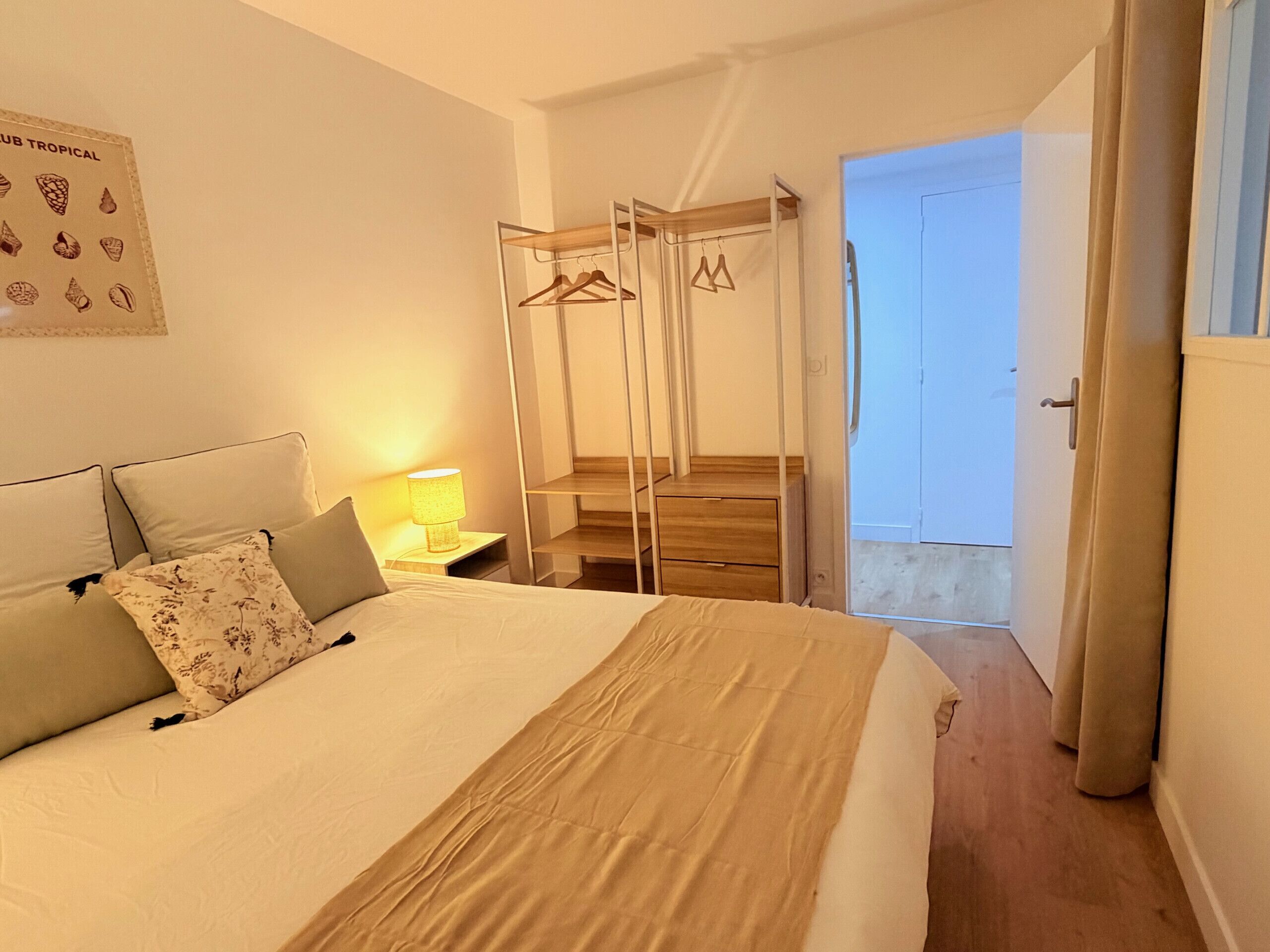 A bedroom with a bed, a nightstand with a lamp, a wardrobe, and a door leading to a balcony.
