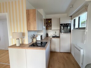 Eine moderne Küche mit integriertem Mikrowellenherd, Backofen und Kühlschrank, Holzschränken und einer gestreiften Wand.