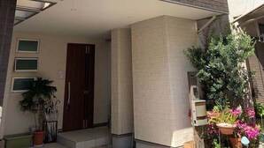 A multi-story residential building with a balcony, a door, and potted plants. - Takara House (Tokyo)