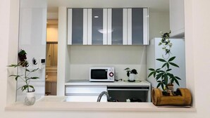 A compact kitchen with a microwave, sink, and cabinets. - Takara House (Tokyo)