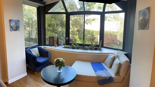 A room with a large window, a blue sofa, a small table with a vase, and a bench with a towel. - KER MARINE : Villa La Baule (La Baule-Escoublac)