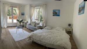 A bedroom with a large bed, two bedside tables, a small table with a vase of flowers, and a window with curtains. - KER MARINE : Villa La Baule (La Baule-Escoublac)