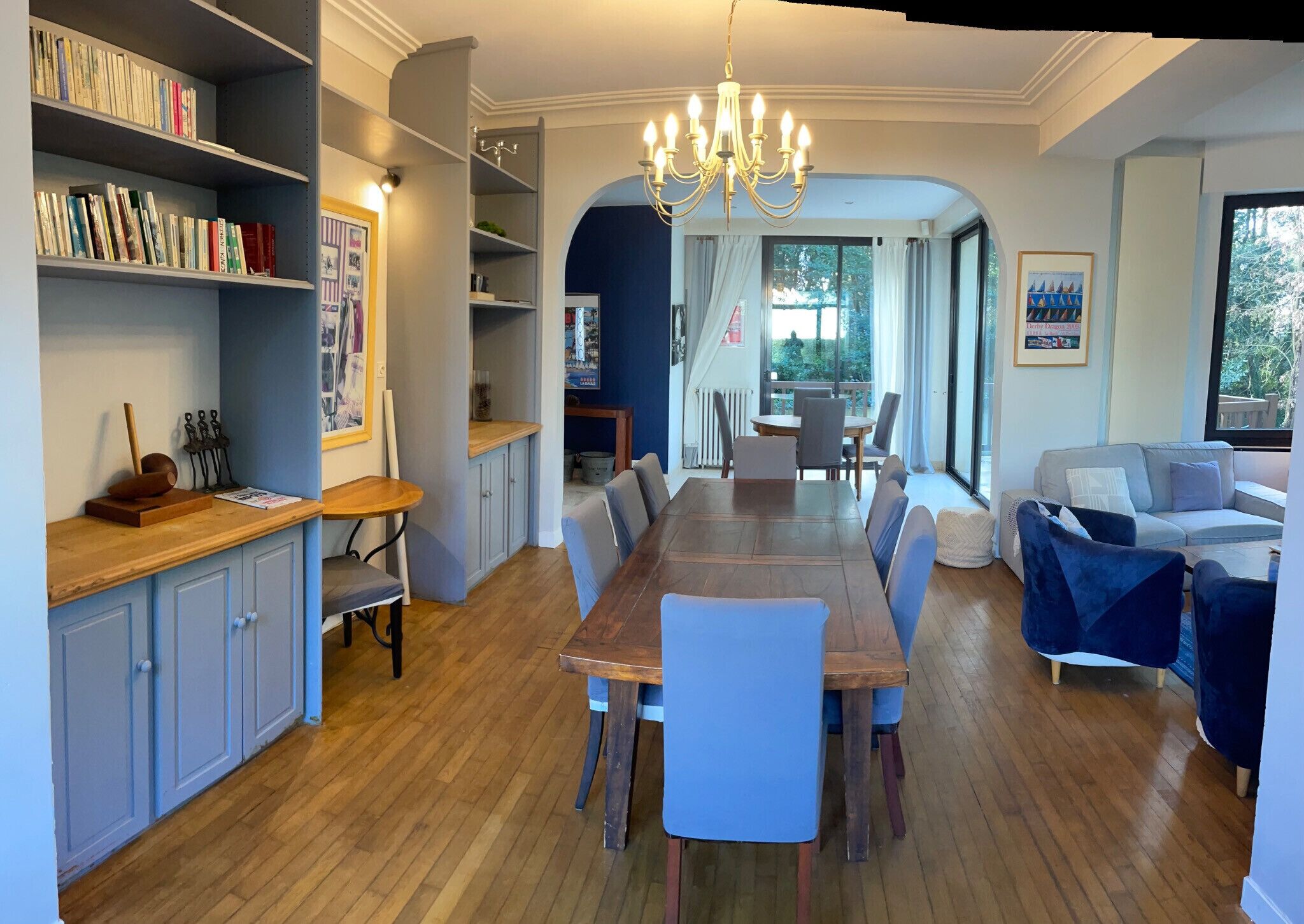A spacious living area with a dining table, chairs, a sofa, and a bookshelf.