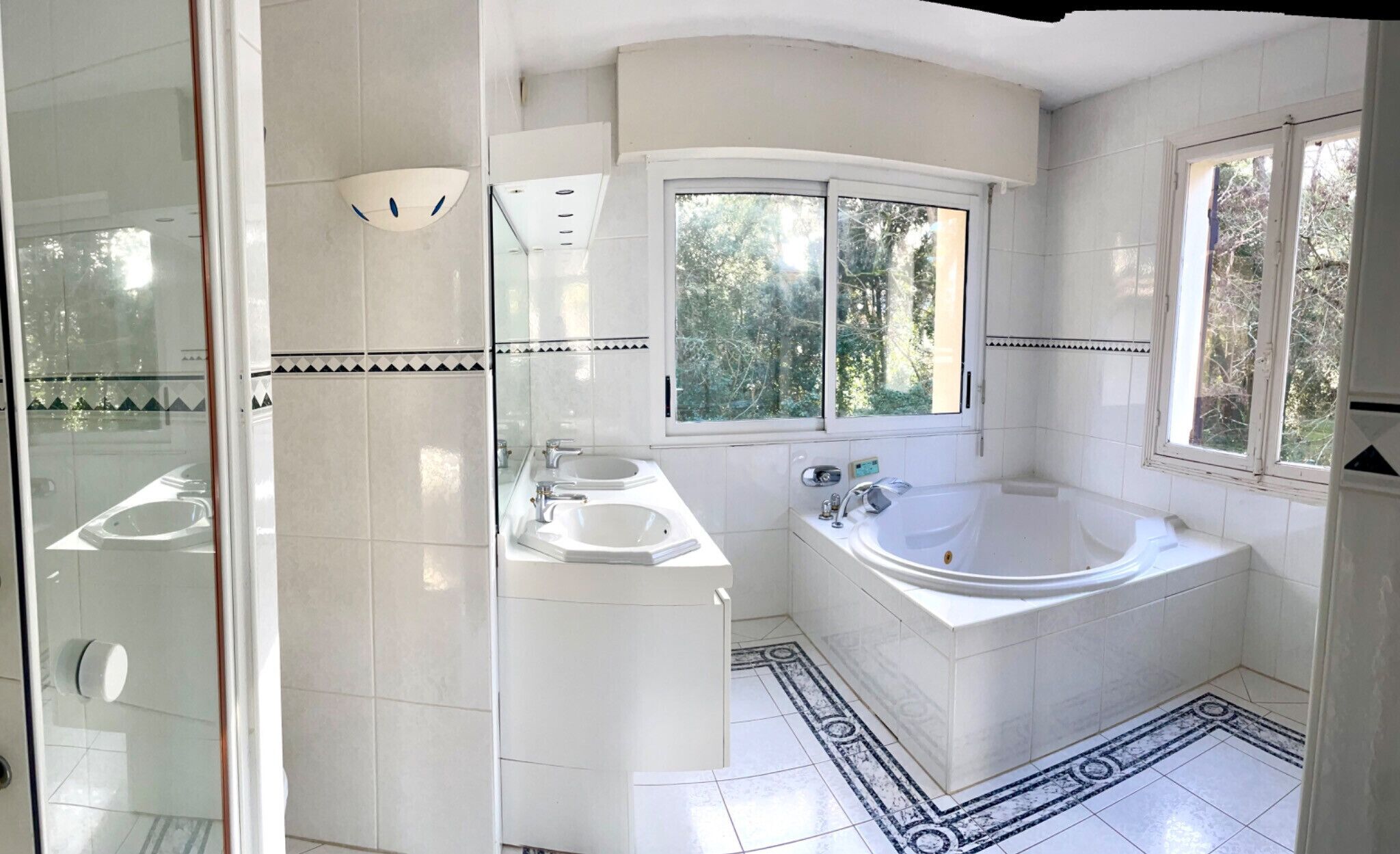 Ein modernes Badezimmer mit einer Badewanne, zwei Waschbecken und einem großen Fenster.