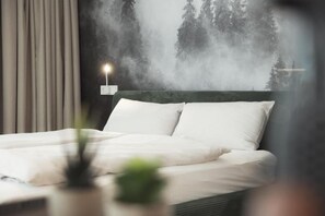Une chambre à coucher comprenant un lit, une table de chevet, une lampe fixée au mur et une fresque murale sur le thème de la forêt.