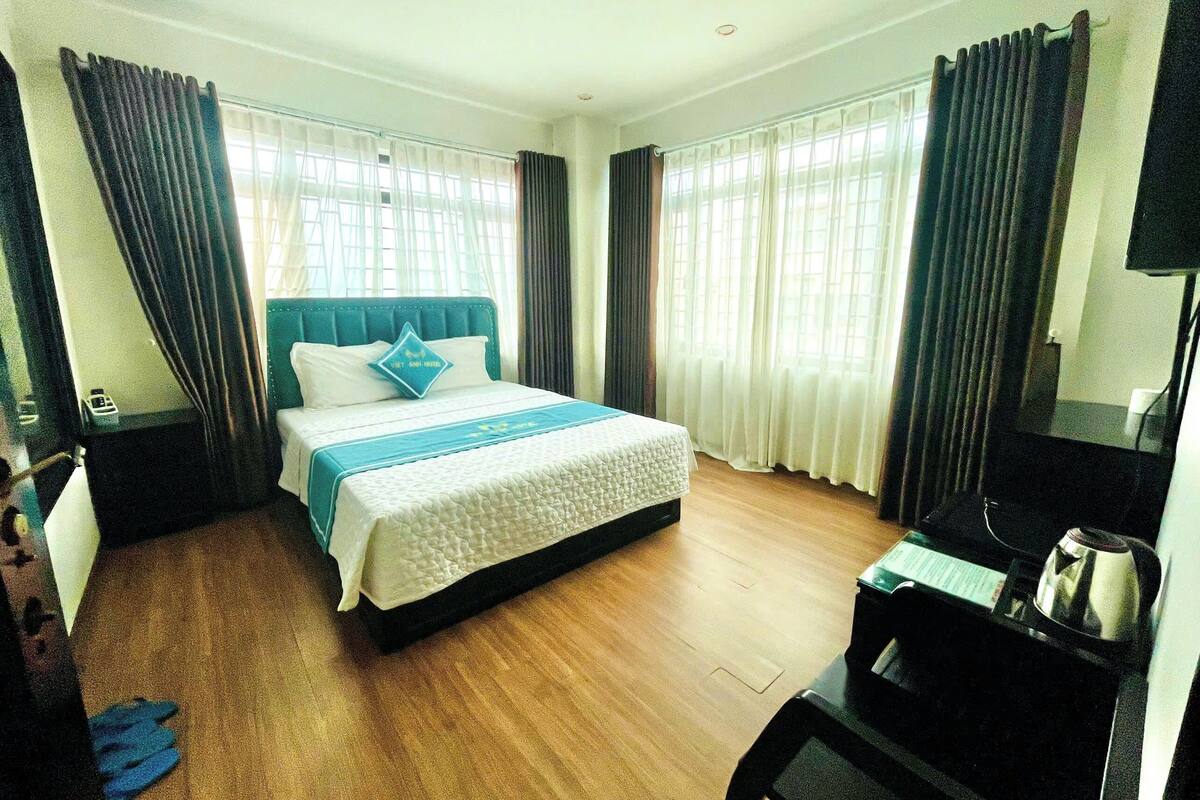 A hotel room with a bed, curtains, a television, and a coffee maker.