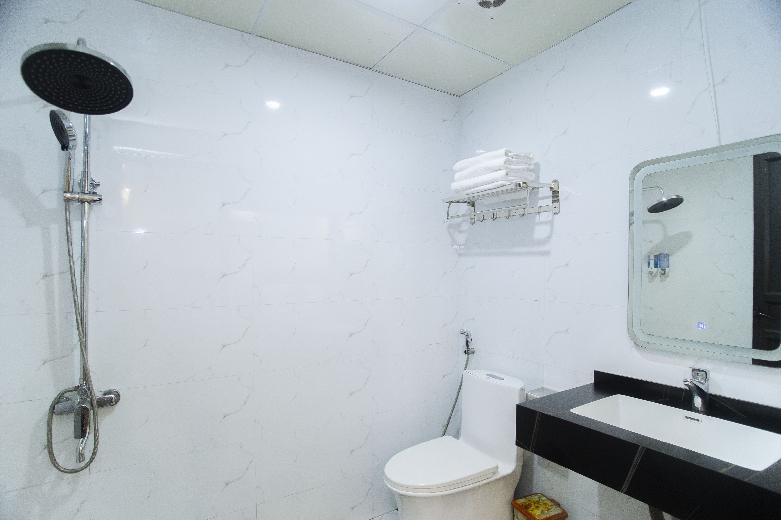 A bathroom with a shower, toilet, sink, and towel rack.