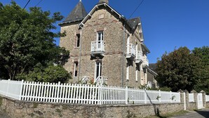 A stone building with multiple windows and a white picket fence.
