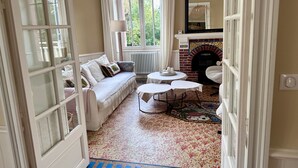 A room with a sofa, a fireplace, a round table, and a patterned carpet.