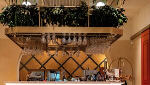 A bar area with a patterned backsplash, bar stools, and hanging plants.