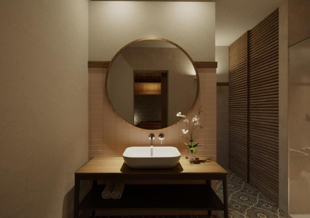 A bathroom with a round mirror, a rectangular sink, and a small vase with flowers.
