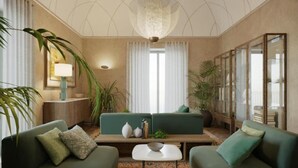 A living room with two green sofas, a coffee table, a chandelier, and a large window with curtains.
