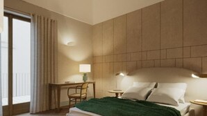 A hotel room with a bed, a desk, a chair, and a window with curtains.