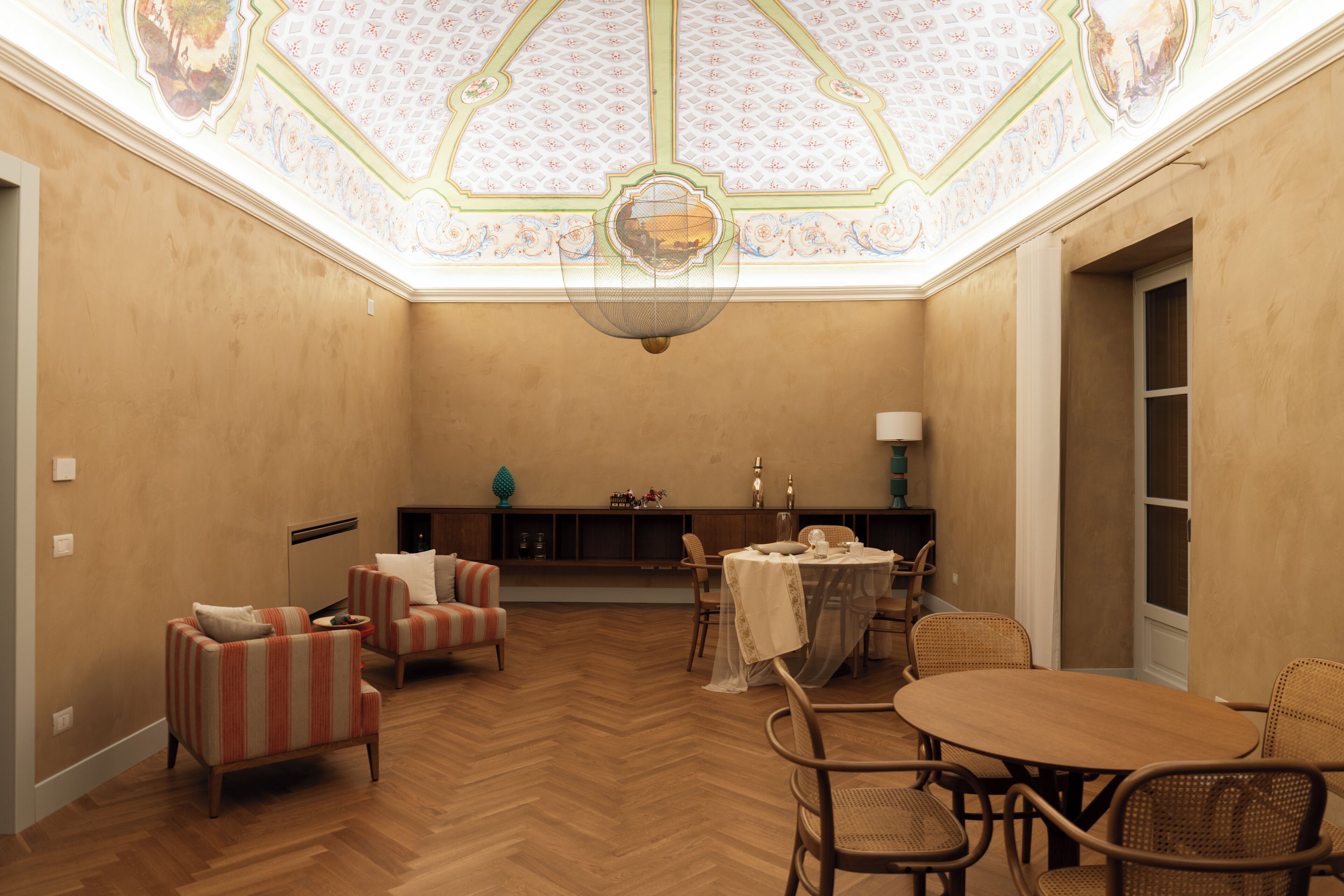 Uma sala de jantar com mesa e cadeiras de madeira, um candelabro e teto decorativo.