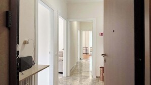 A hotel hallway with a reception desk, a fire exit sign, and a door leading to a room. - Appartamento Belvedere - Affitti Brevi Italia (Lecco)