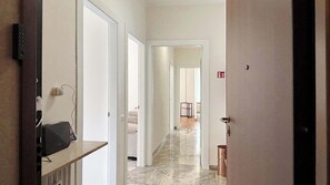 Ein Hotelgang mit einer Rezeption, einem Fluchtwegschild und einer Tür zu einem Zimmer.