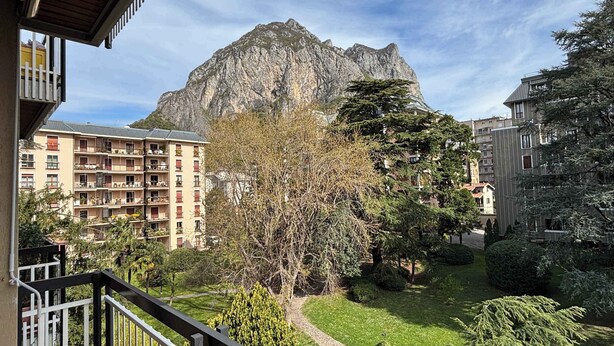 A residential area with a mountain in the background, a balcony with railings, and a pathway. - Appartamento Belvedere - Affitti Brevi Italia (Lecco)