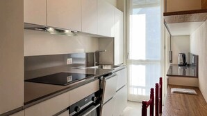 A modern kitchen with a stainless steel range, a built-in oven, and a coffee maker on the countertop. - Appartamento Belvedere - Affitti Brevi Italia (Lecco)