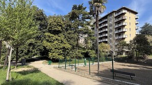 Ein Park mit einem Weg, Bäumen und einem mehrstöckigen Gebäude mit Balkonen.