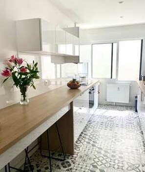 Eine moderne Küche mit einer Holzauskładung, weißen Schränken, einer Blumenvase und einem gemusterten Boden.