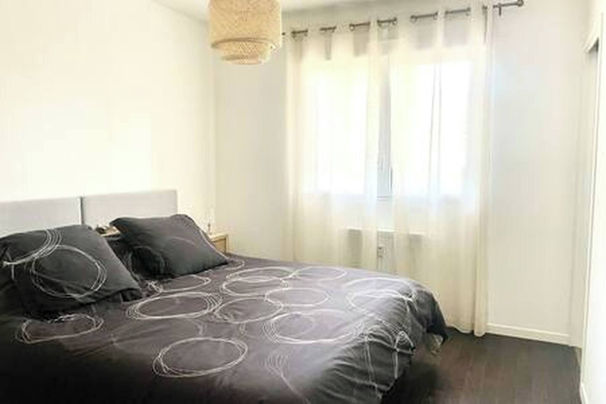 Une chambre à coucher avec un lit, des rideaux et un luminaire suspendu.