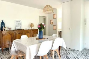 Ein Essbereich mit einem Tisch für vier Personen, einer Blumenvase, einem Holzschrank und einer Pendelleuchte.