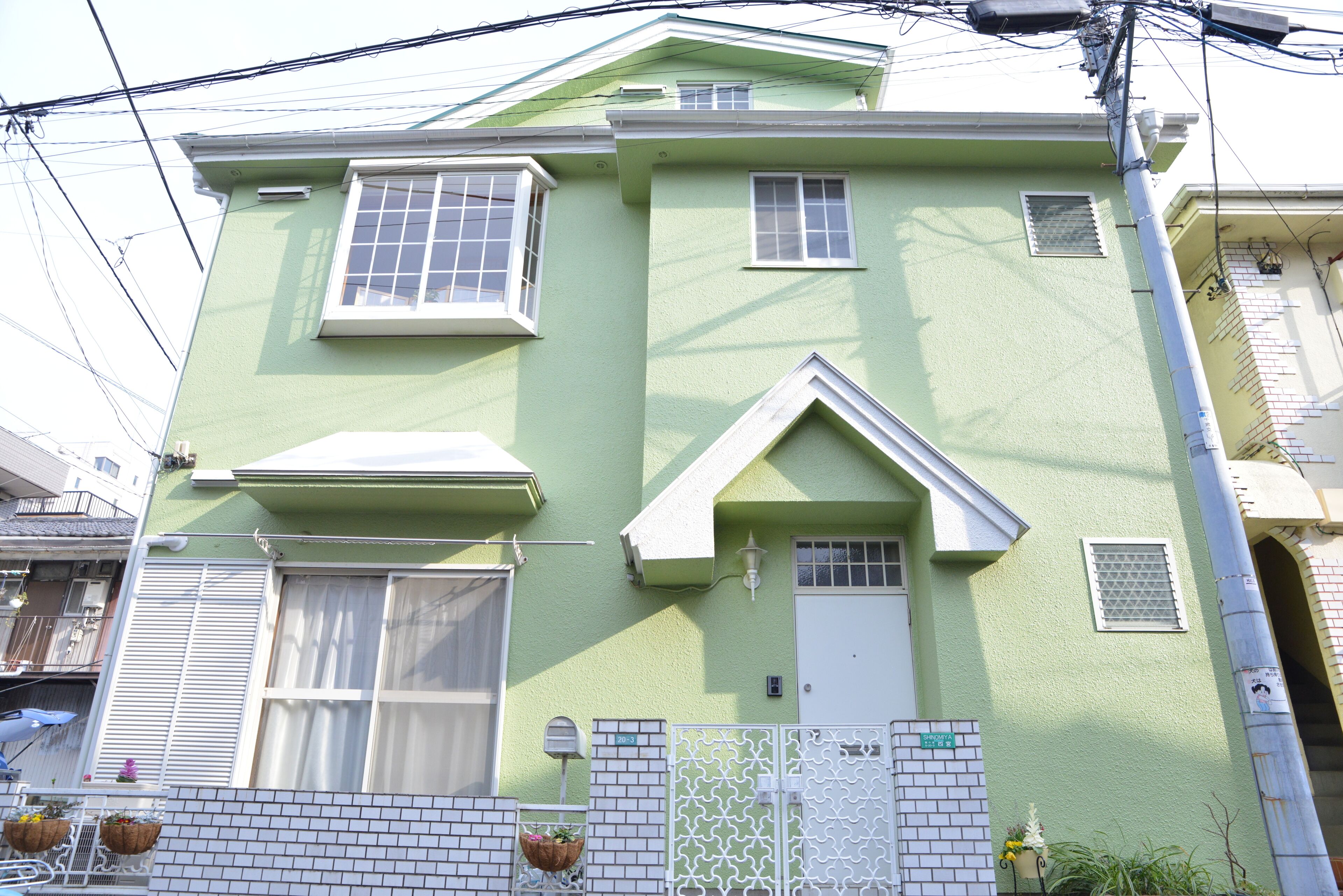 A two-story building with a green facade, white trim, and multiple windows.