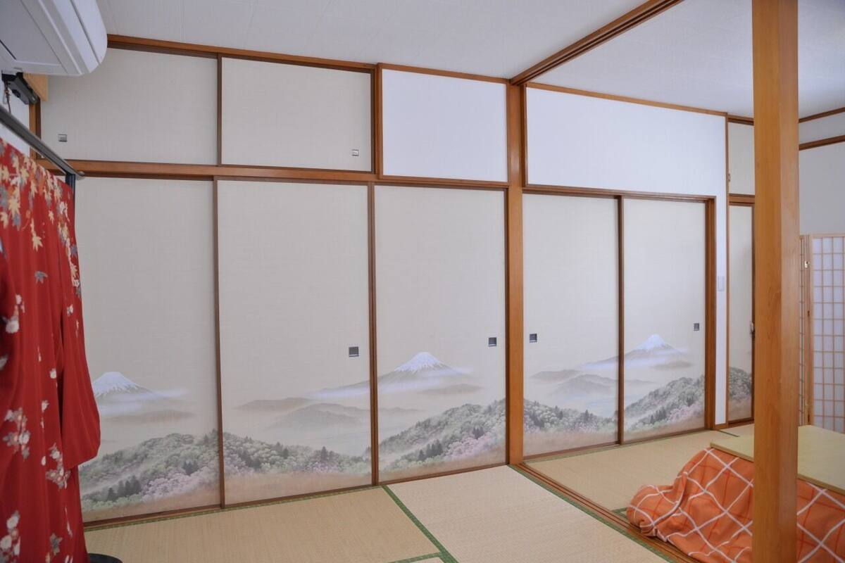 A traditional Japanese room with tatami flooring, shoji screens, and a view of a mountain landscape.
