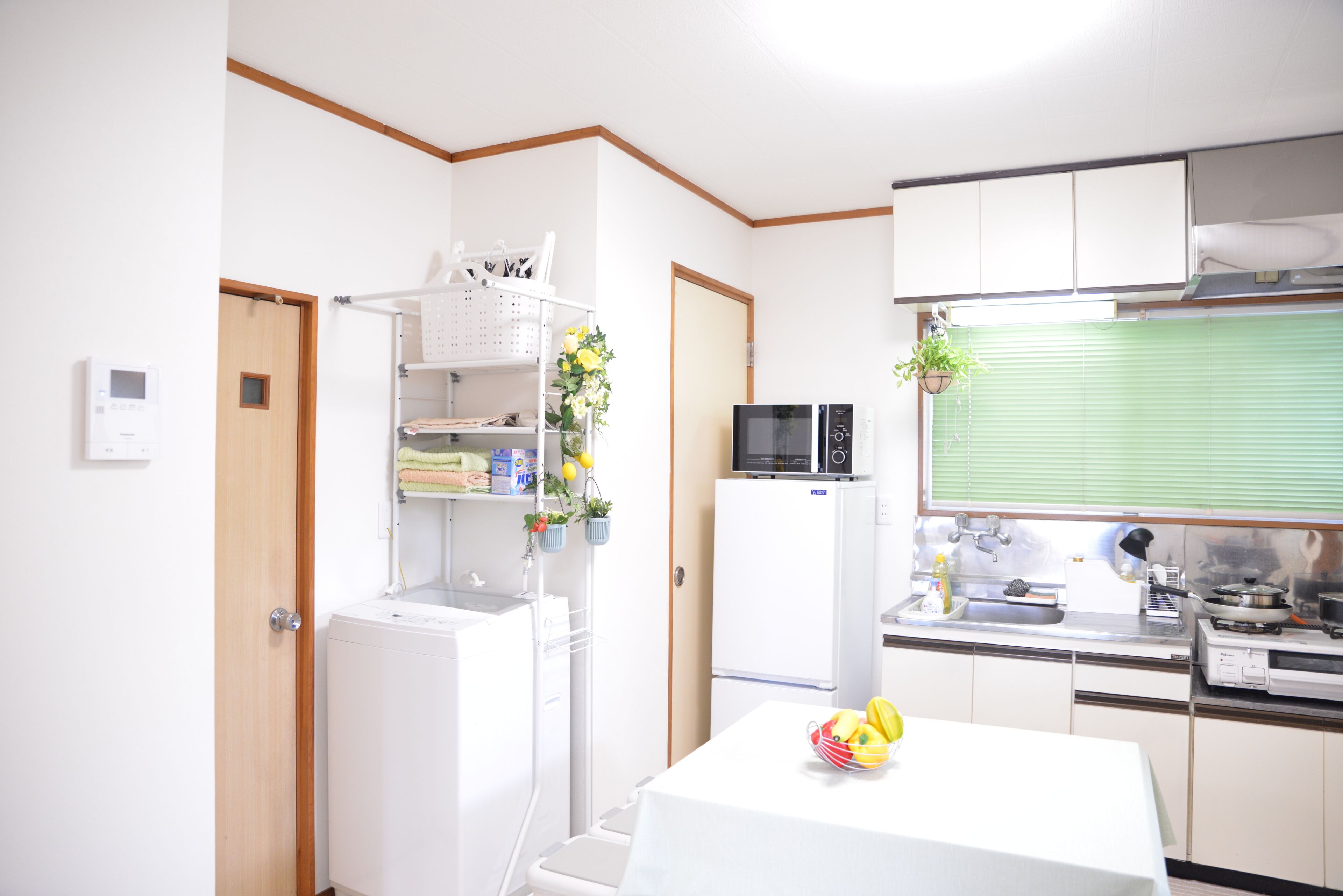 A compact kitchen with a microwave, sink, and a table with a fruit bowl.