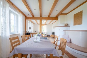 A dining area with a table set for four, wooden chairs, a white tablecloth, and a bench with cushions. - Holiday Home Hofgut Wörner – Ground Floor Apartment / Kneipp / Vineyards / Terrace / Winery (Durbach)