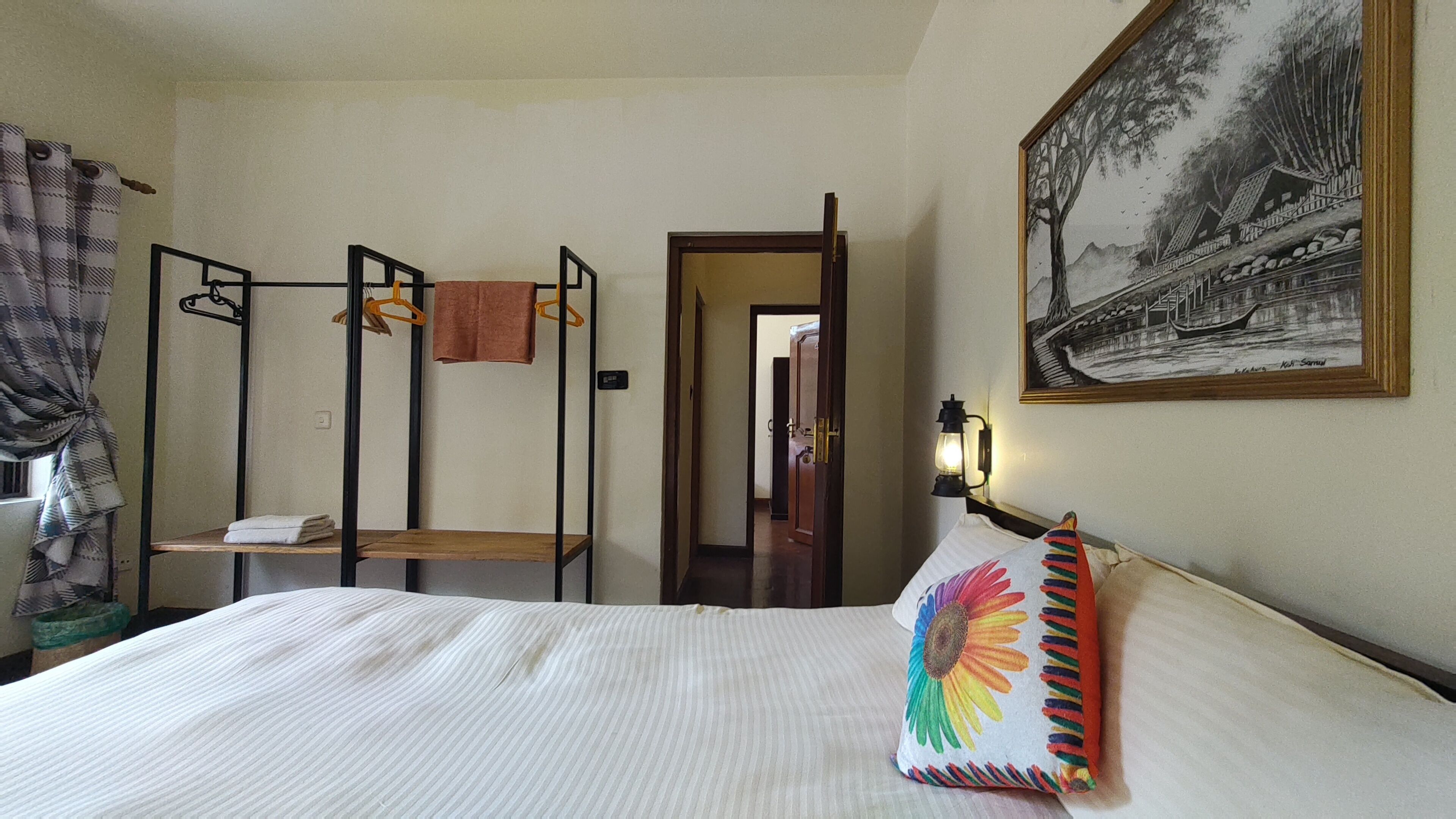 Une chambre d’hôtel avec un lit superposé, un tableau au mur et un lit agrémenté d’un oreiller coloré.