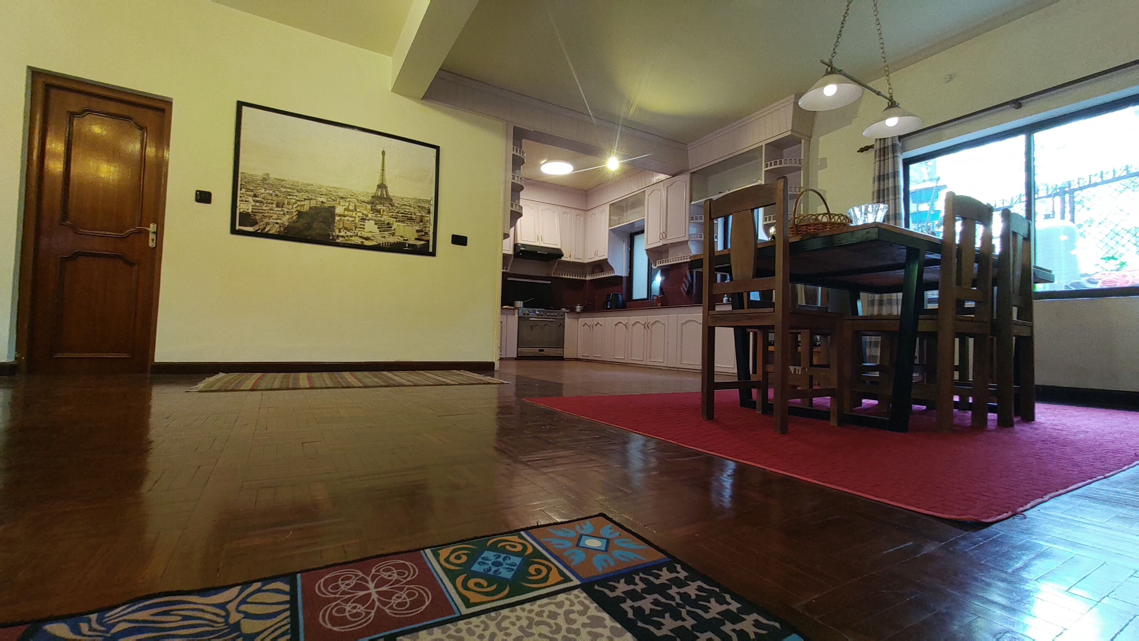Una cocina amplia con armarios de madera, un comedor con alfombra roja y un ventanal grande.