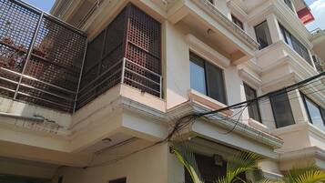 A multi-story building with balconies, a gated entrance, and potted plants.