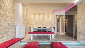 A modern interior with a stone wall, a white bench, and a table with red cushions. - Stone Build Modern and Traditional Villa near Heraklion (Agios Syllas)