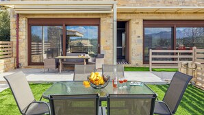 A modern outdoor patio with a glass table, wicker chairs, and a fruit bowl. - Stone Build Modern and Traditional Villa near Heraklion (Agios Syllas)