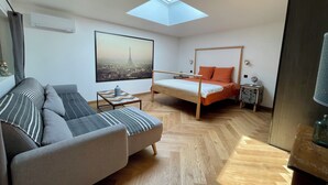 Ein modernes Zimmer mit Oberlicht, einem Bett, einer Couch und einem kleinen Tisch.