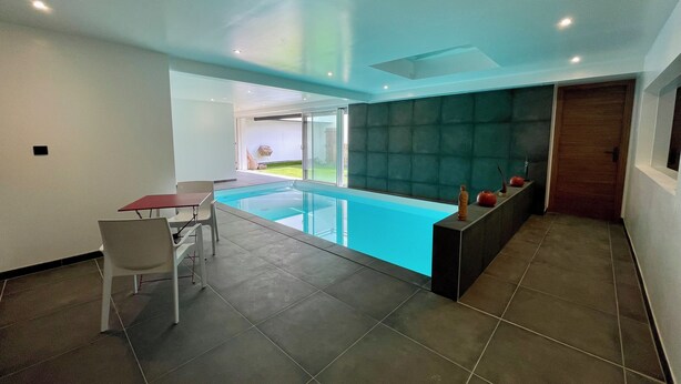 Ein modernes Interieur mit Schwimmbad, Essbereich und großem Fenster.