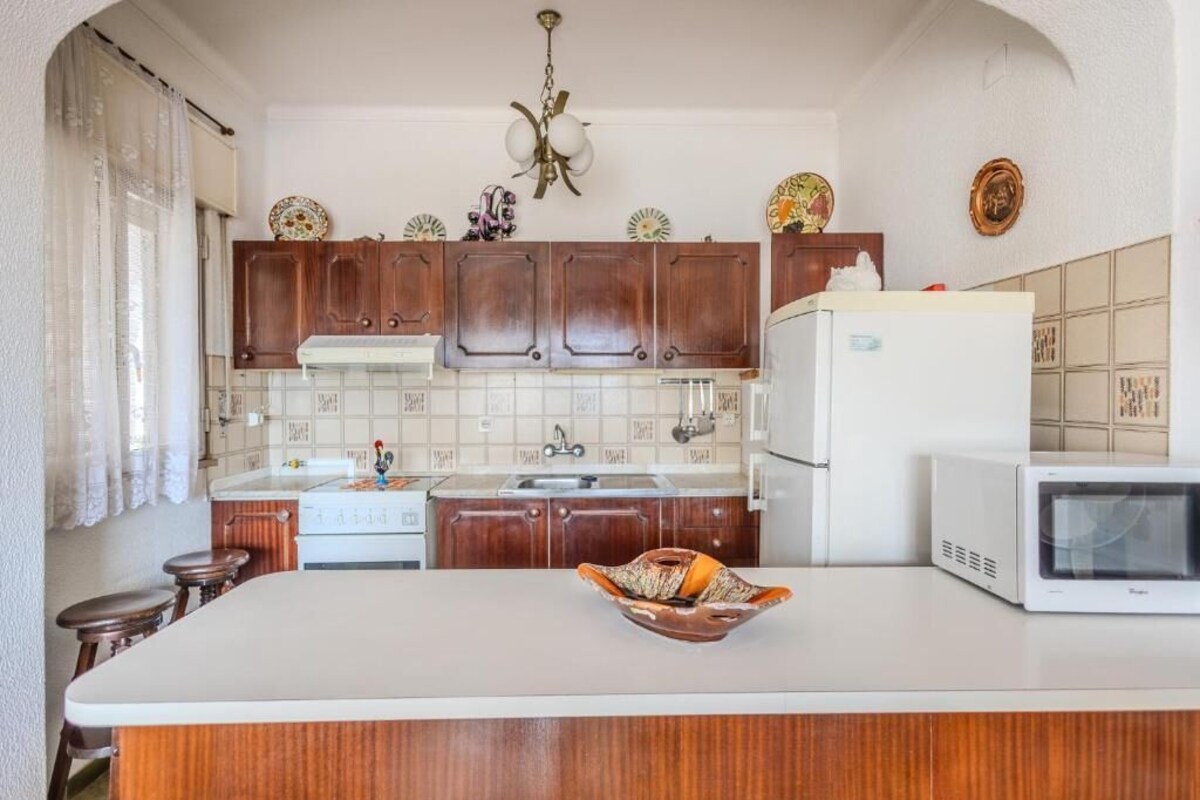 A kitchen with wooden cabinets, a white refrigerator, a microwave, and a decorative bowl on the counter.