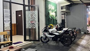Una motocicleta estacionada en un espacio cubierto con piso de baldosas, un banco y un bote de basura.
